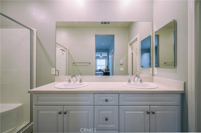 ensuite bathroom featuring double vanity, an enclosed shower, visible vents, and a sink