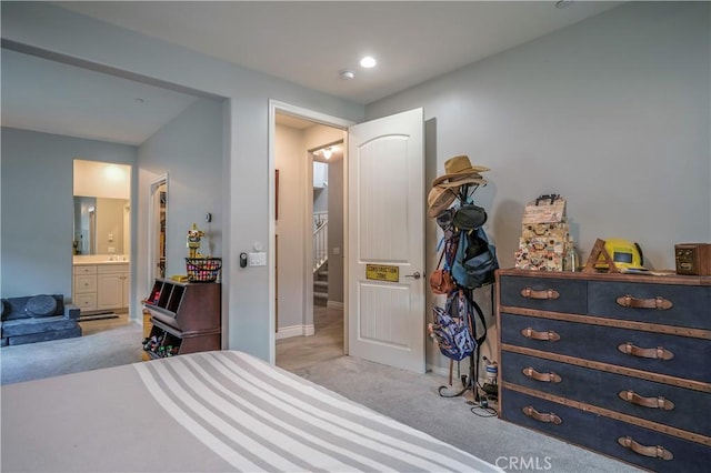 bedroom with connected bathroom, baseboards, and carpet flooring