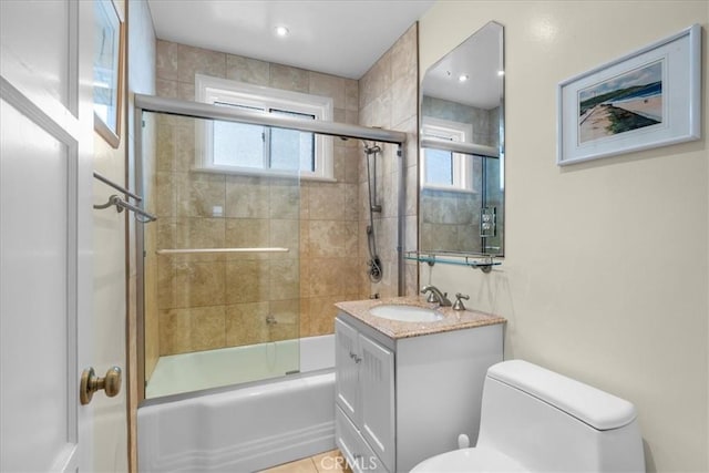 full bathroom featuring vanity, bath / shower combo with glass door, and toilet