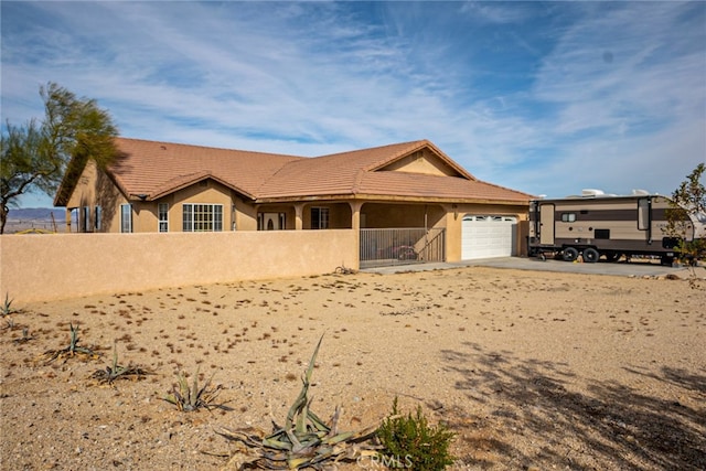 view of front of house featuring a fenced front yard, stucco siding, a tile roof, and a garage