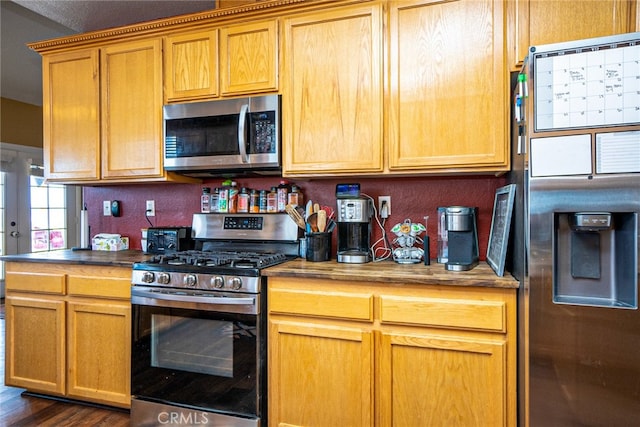 kitchen with stainless steel appliances, dark wood finished floors, and wood counters