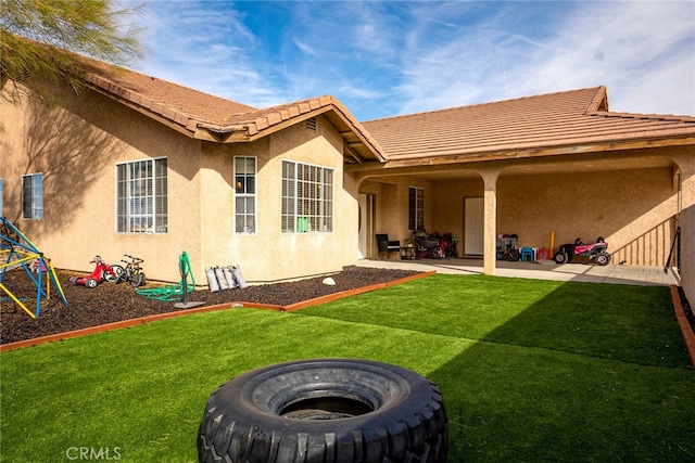 back of property featuring a tile roof, a yard, a patio area, and stucco siding