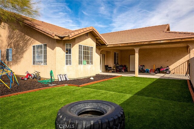 74384 Rocky Rd Unit 29, Palms, CA 92277 - rear view of property featuring stucco siding, a yard, a patio area, a tiled roof, and an outdoor fire pit