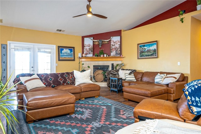 living area featuring visible vents, vaulted ceiling, a tile fireplace, french doors, and wood finished floors