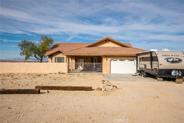 view of front of house featuring a tiled roof, an attached garage, dirt driveway, and stucco siding