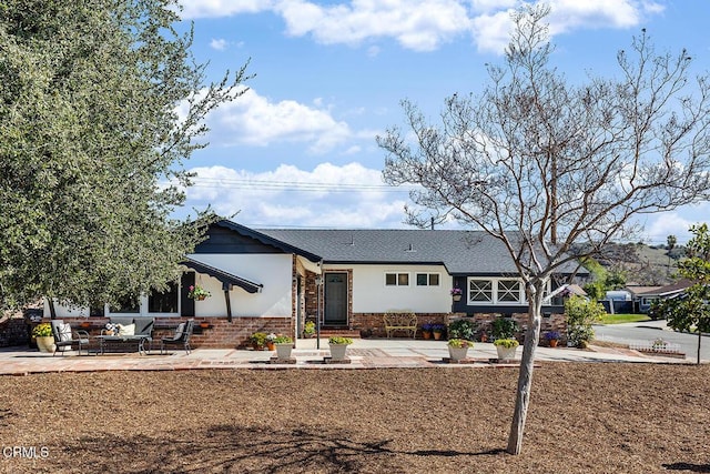 view of front facade with an outdoor living space and a patio