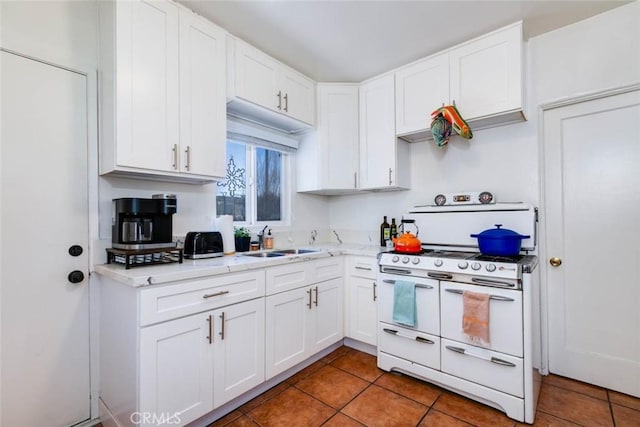 kitchen featuring white cabinetry, tile patterned flooring, sink, and range with two ovens