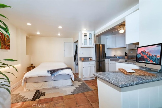 kitchen with stainless steel refrigerator, white cabinetry, light tile patterned floors, ceiling fan, and kitchen peninsula