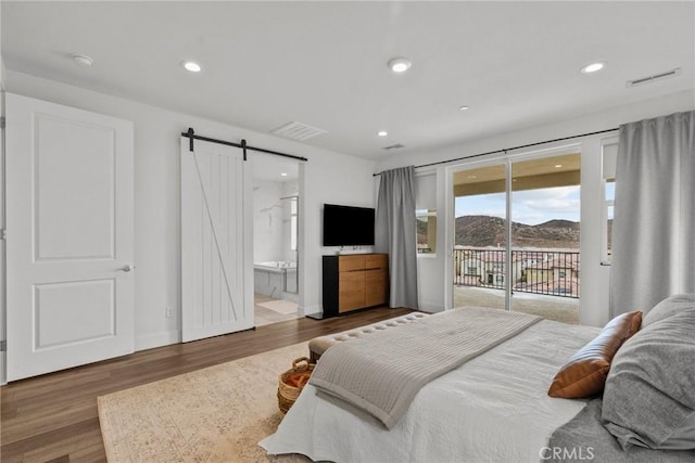 bedroom with access to exterior, dark wood-type flooring, a barn door, and ensuite bathroom