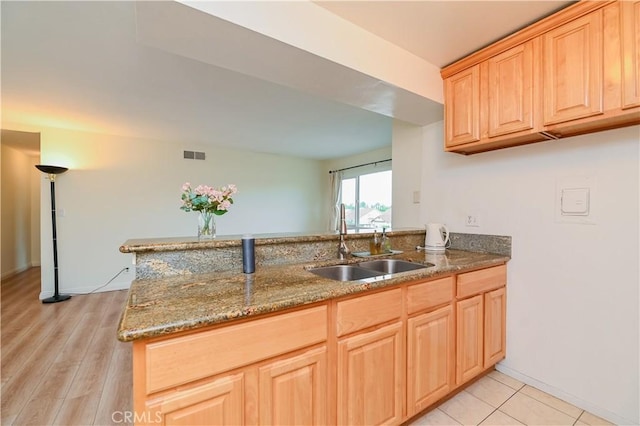 kitchen with sink, light brown cabinets, kitchen peninsula, and stone counters