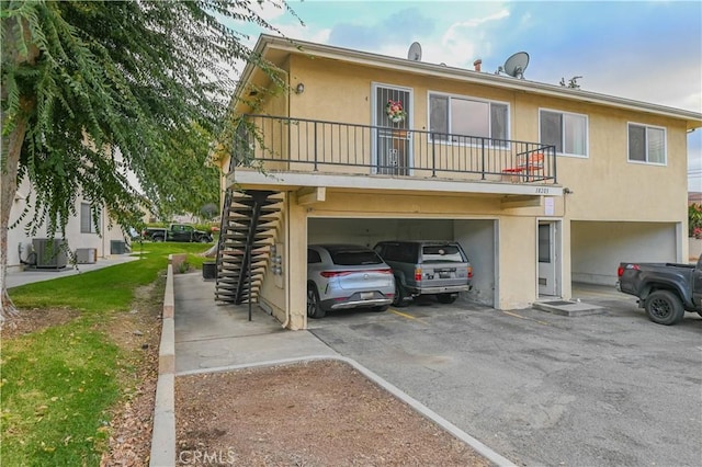 rear view of property with central AC unit, a garage, and a balcony