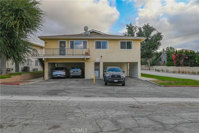 view of front of property with a garage, a balcony, and central AC