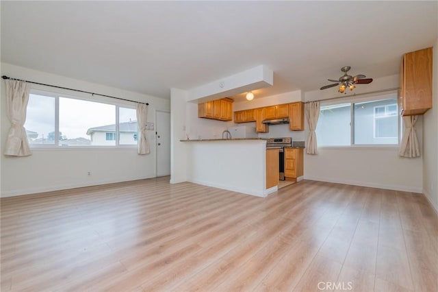 kitchen with light hardwood / wood-style flooring, stainless steel range with electric cooktop, kitchen peninsula, and ceiling fan