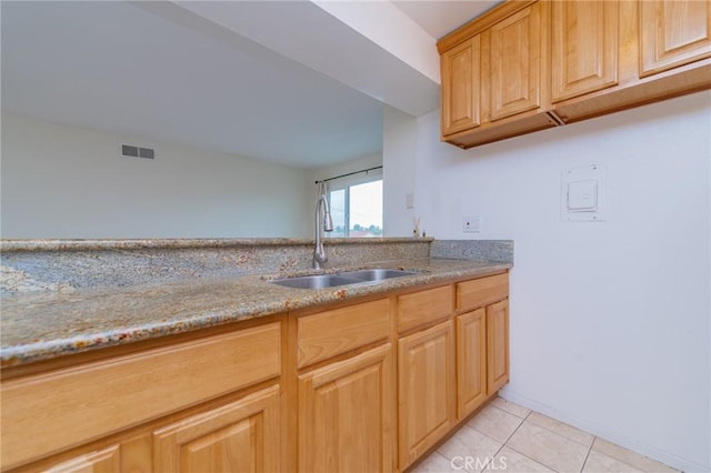 kitchen with light tile patterned flooring, light stone countertops, and sink