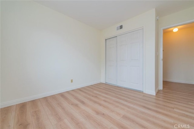 unfurnished bedroom with light wood-type flooring and a closet