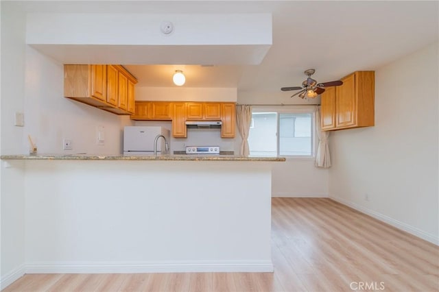 kitchen featuring white refrigerator, range, kitchen peninsula, and light stone counters