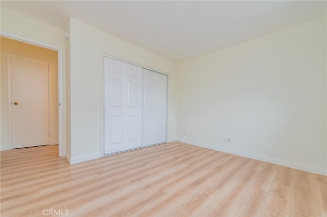 unfurnished bedroom featuring light hardwood / wood-style flooring and a closet