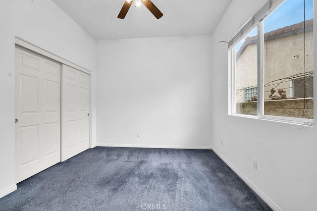 unfurnished bedroom with dark carpet, a ceiling fan, baseboards, and a closet