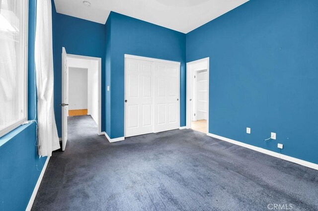 unfurnished bedroom featuring carpet flooring, baseboards, and a closet