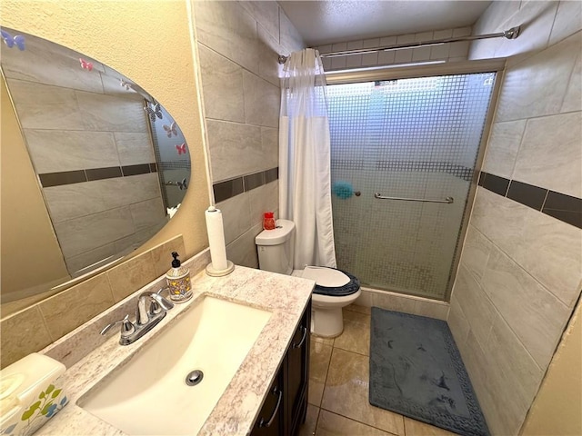 bathroom with tile walls, vanity, curtained shower, tile patterned floors, and toilet