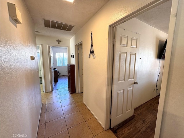 hallway featuring a textured ceiling and light tile patterned flooring