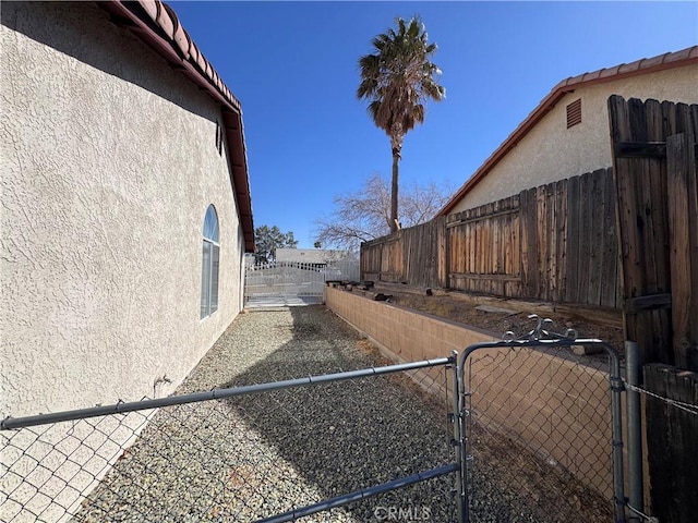 view of property exterior with stucco siding, a gate, and a fenced backyard