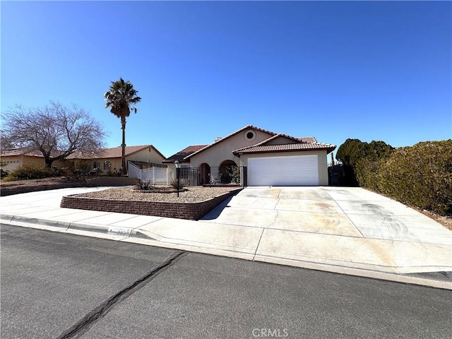 ranch-style home featuring a tile roof, concrete driveway, an attached garage, fence, and stucco siding