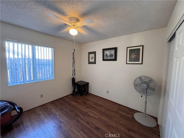 unfurnished bedroom featuring dark hardwood / wood-style flooring, ceiling fan, and a textured ceiling