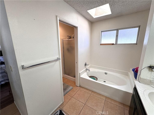 bathroom featuring a skylight, independent shower and bath, tile patterned flooring, vanity, and a textured ceiling