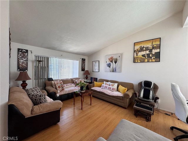 living room with lofted ceiling, light hardwood / wood-style floors, and a textured ceiling