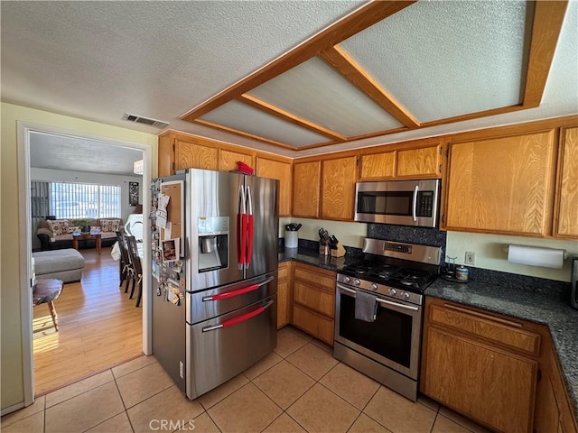 kitchen featuring appliances with stainless steel finishes, a textured ceiling, and light tile patterned floors