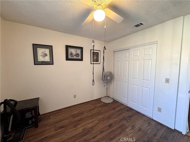 bedroom featuring ceiling fan, a textured ceiling, dark hardwood / wood-style flooring, and a closet