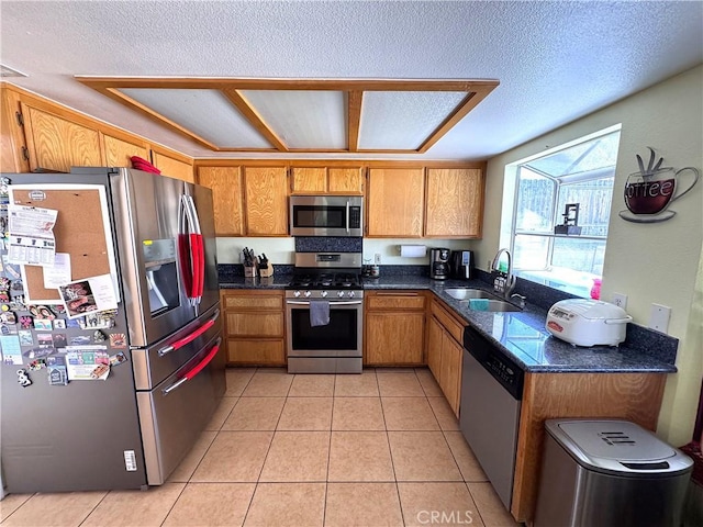 kitchen with light tile patterned flooring, appliances with stainless steel finishes, sink, and a textured ceiling