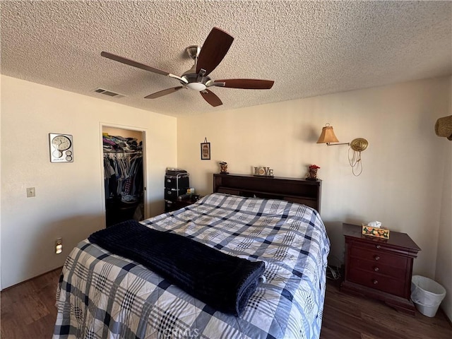 bedroom with wood finished floors, visible vents, a ceiling fan, a closet, and a textured ceiling