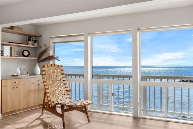 sunroom / solarium featuring a water view and a beach view