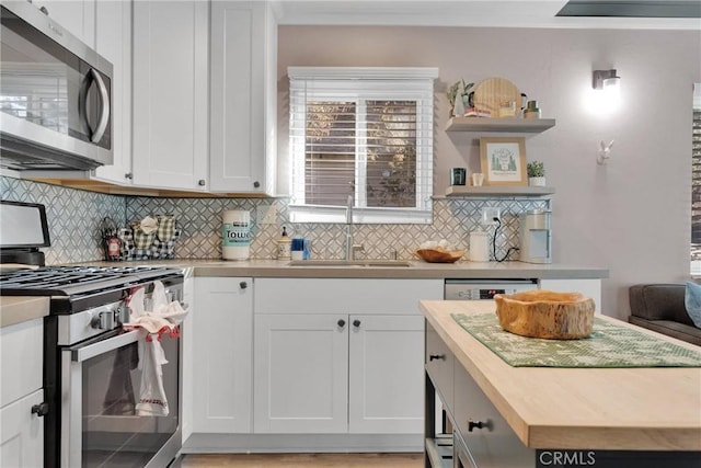 kitchen with sink, wooden counters, white cabinets, backsplash, and stainless steel appliances