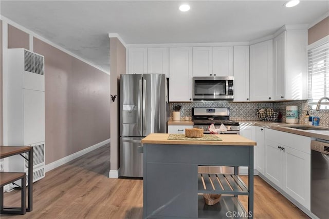 kitchen with sink, appliances with stainless steel finishes, white cabinetry, tasteful backsplash, and a kitchen island