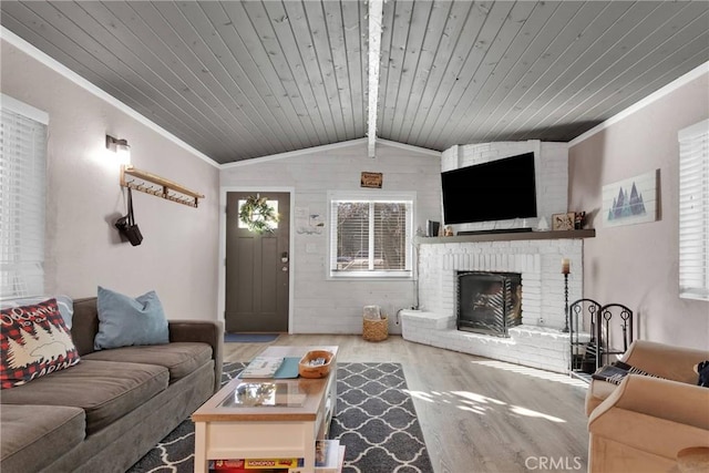 living room featuring vaulted ceiling with beams, wood ceiling, crown molding, wood-type flooring, and a brick fireplace