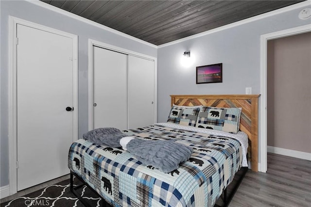 bedroom featuring crown molding, dark wood-type flooring, wood ceiling, and a closet