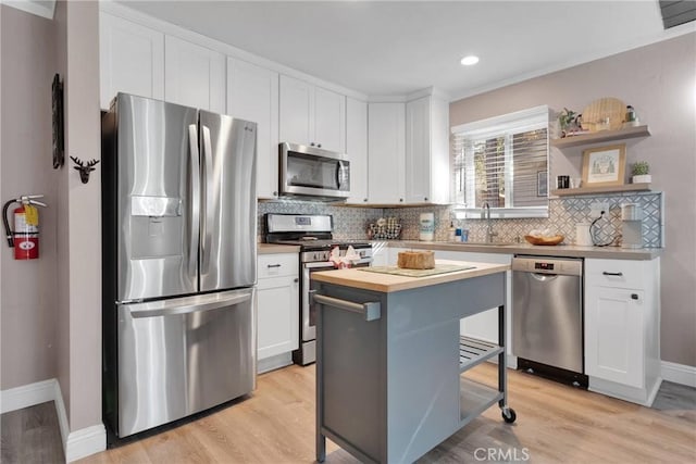 kitchen with a kitchen island, appliances with stainless steel finishes, sink, white cabinets, and backsplash