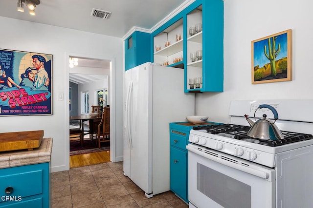 kitchen with blue cabinetry, white appliances, and light tile patterned flooring