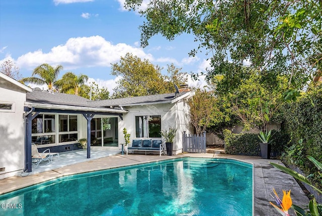 rear view of property with an outdoor living space, a fenced in pool, and a patio area