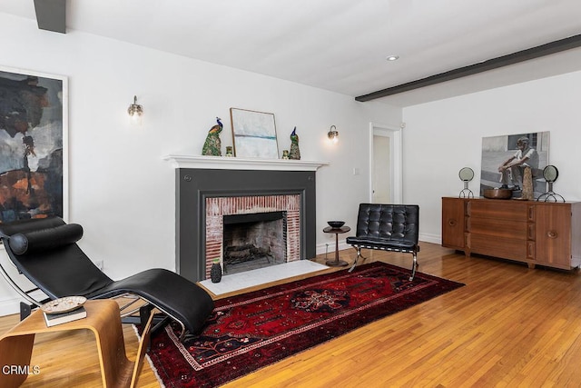 living room with a fireplace, beam ceiling, and hardwood / wood-style floors