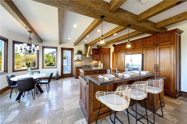 kitchen featuring a breakfast bar, hanging light fixtures, a large island, stainless steel fridge with ice dispenser, and wall chimney range hood