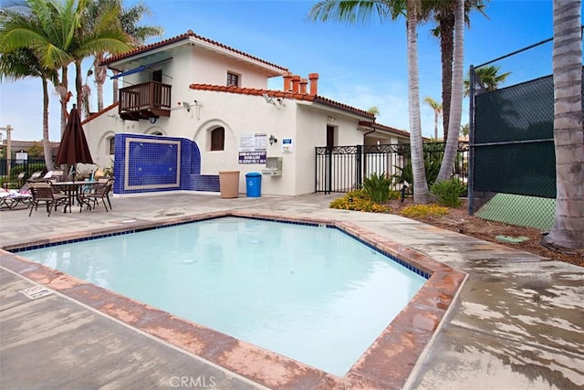 rear view of house featuring a balcony, a community pool, and a patio