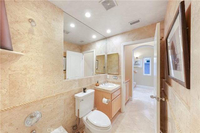 bathroom featuring vanity, toilet, tile patterned flooring, and tile walls