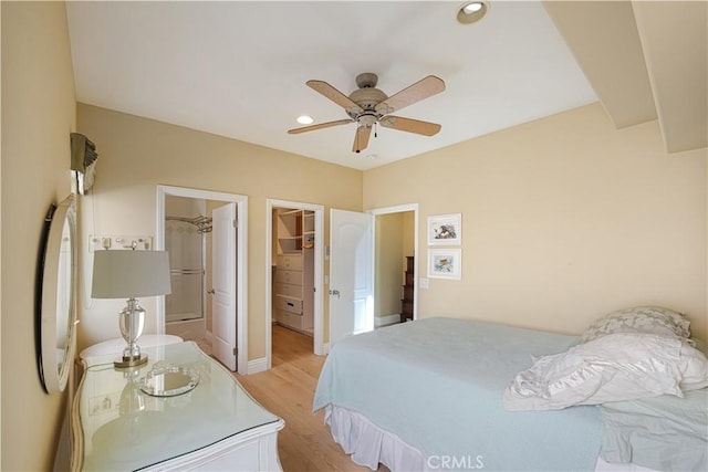 bedroom featuring a walk in closet, light hardwood / wood-style flooring, and ceiling fan