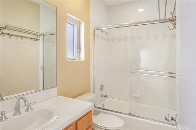 full bathroom featuring vanity, combined bath / shower with glass door, and toilet