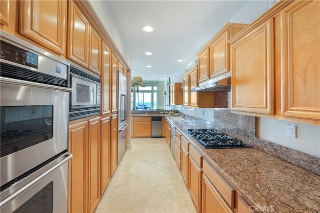 kitchen with sink, light tile patterned floors, stainless steel appliances, light stone countertops, and decorative backsplash