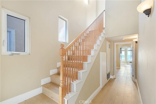 staircase with hardwood / wood-style flooring and a towering ceiling